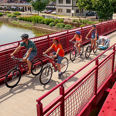 Family riding bicycles over a pedestrian bridge