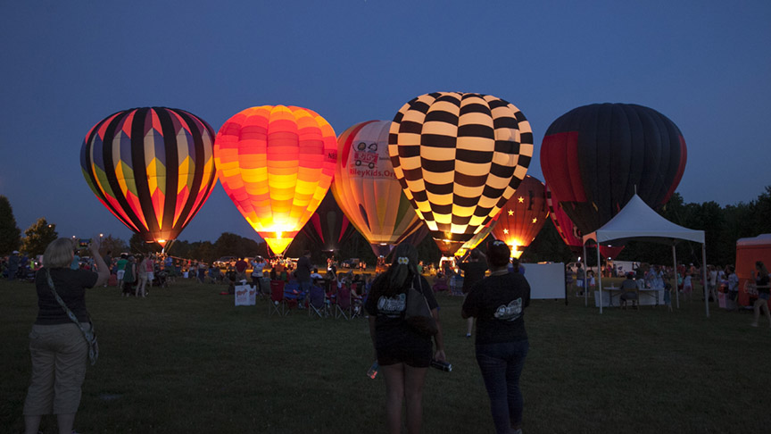 Evening exterior of hot air balloons glowing at the Balloon Glow in Avon