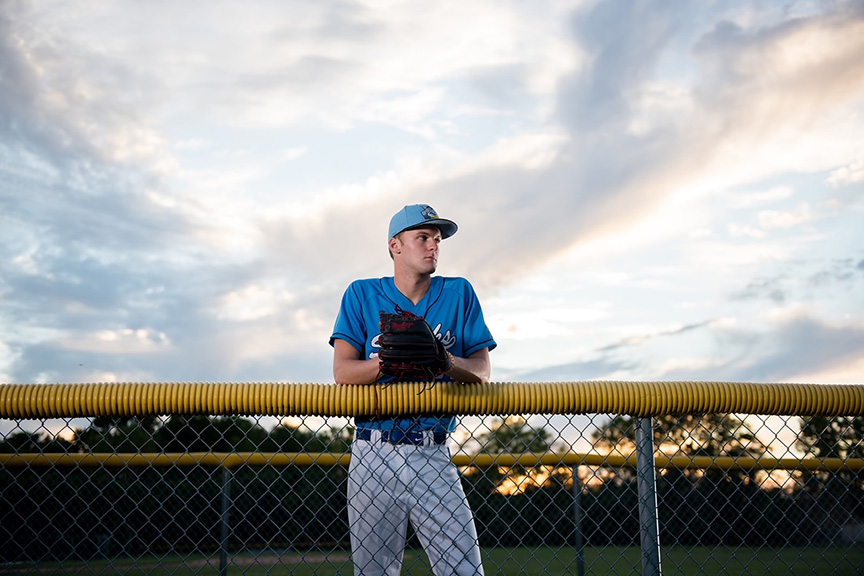 Baseball player leaning against fence