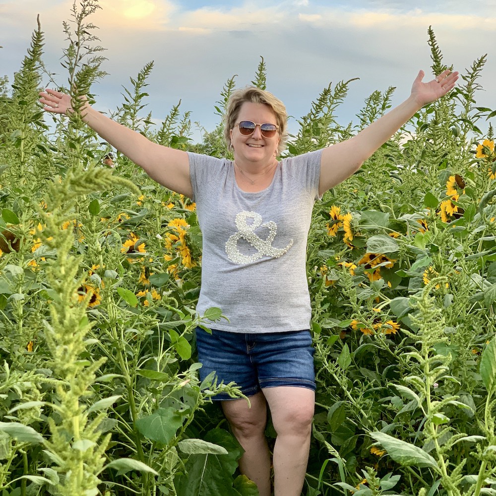 Woman standing surrounded by sunflowers