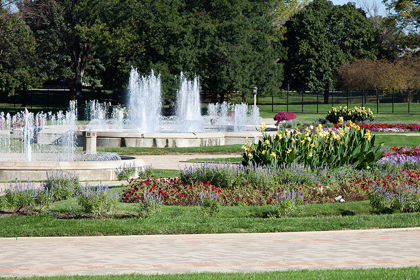 Park with walking path, flowers, and fountains