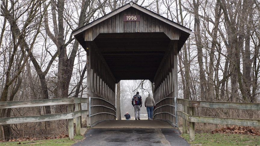 Couple walking through a covered bridge at Pioneer Park in Mooresville
