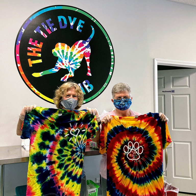 A man and woman hold up tie dyed shirts at the Tie Dye Lab in Avon 