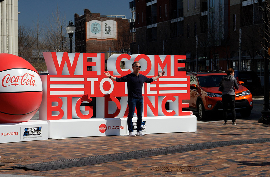 Man posing in front of a sign that says - Welcome to the Big Dance