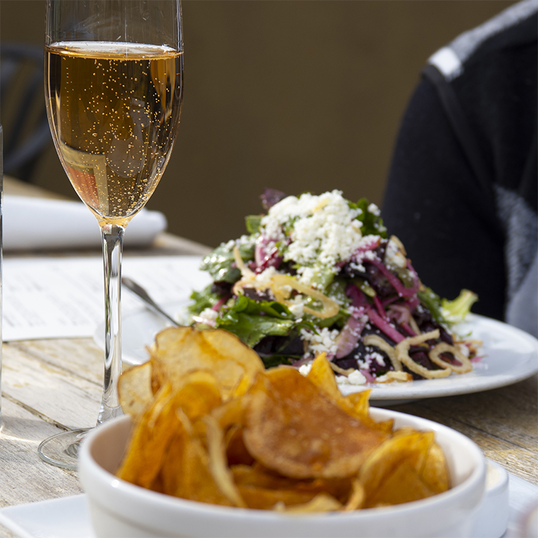 A glass of wine, home fried chips and a beet salad at Bluebeard