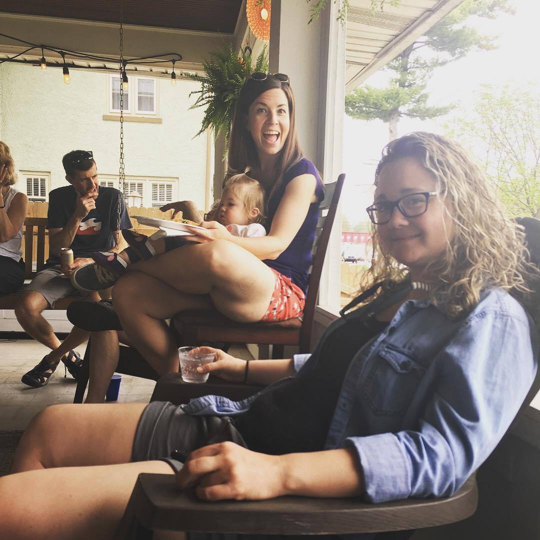 Women sitting at a porch party smile at the camera