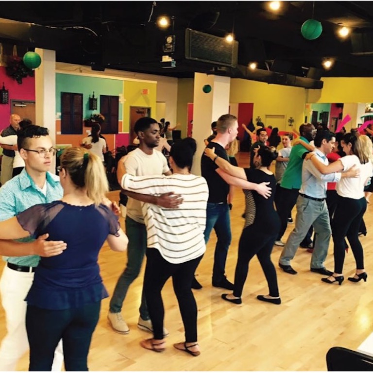 Pairs of people dance in a Latin dance class