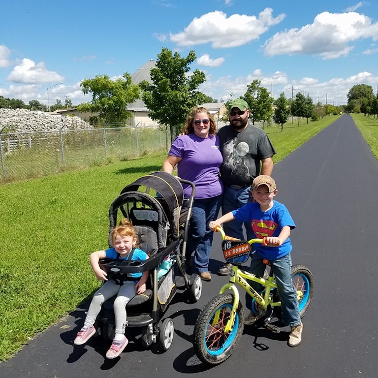 A family of four happily walks along Pennsy Trail