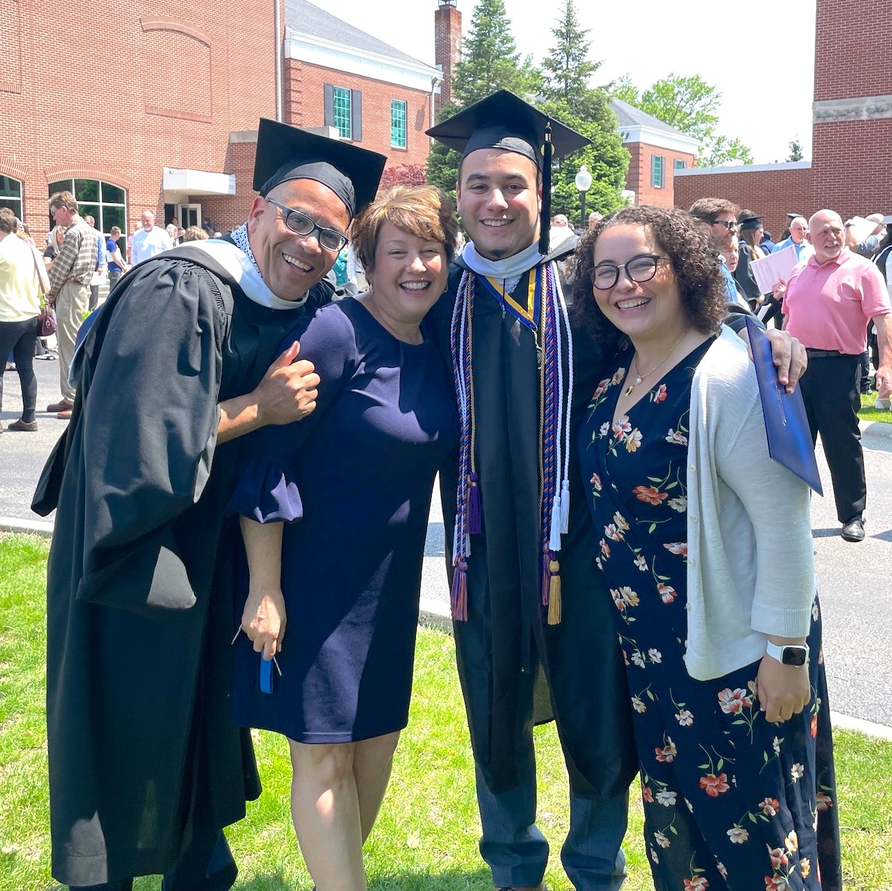 A college graduate poses with his family in cap and gown