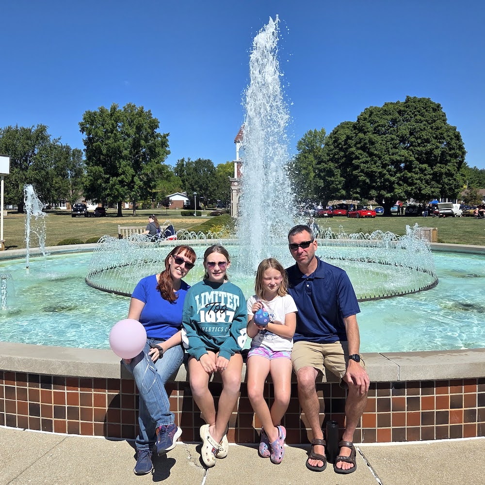 Family posing for a photo sitting on a fountain